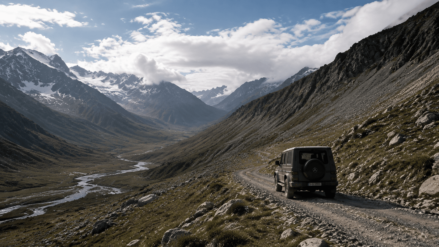Mercedes G-Class 沿高山河谷中的碎石路駛向遠方，車輛融入遼闊山地