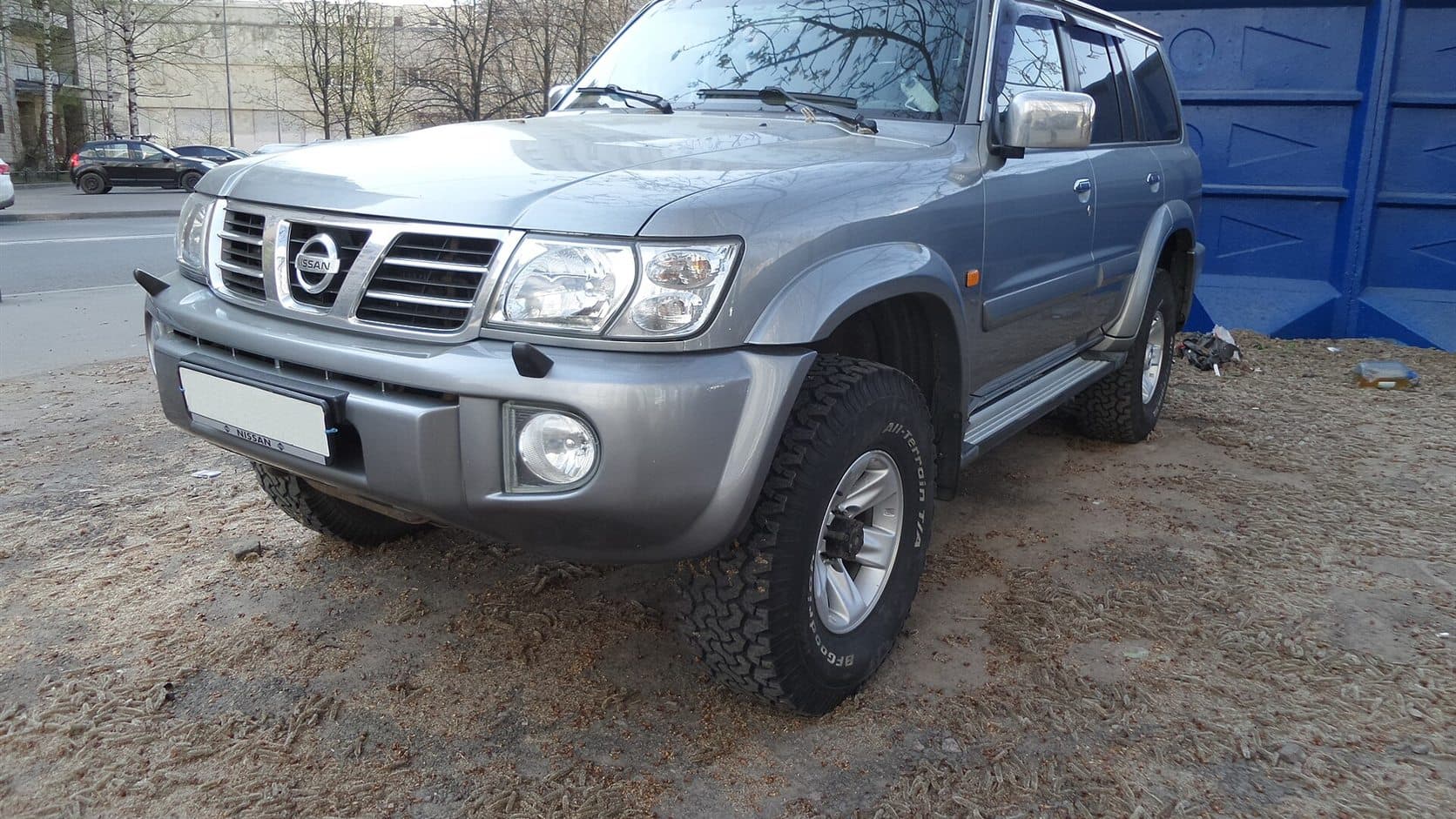 一部銀色 Nissan Patrol Y61 停在城市邊緣的未鋪裝地面上
